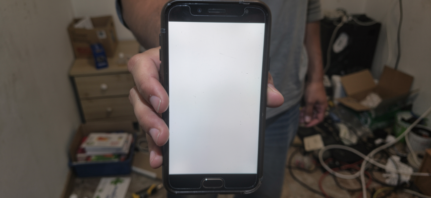 Person holding a budget smartphone with a dim screen